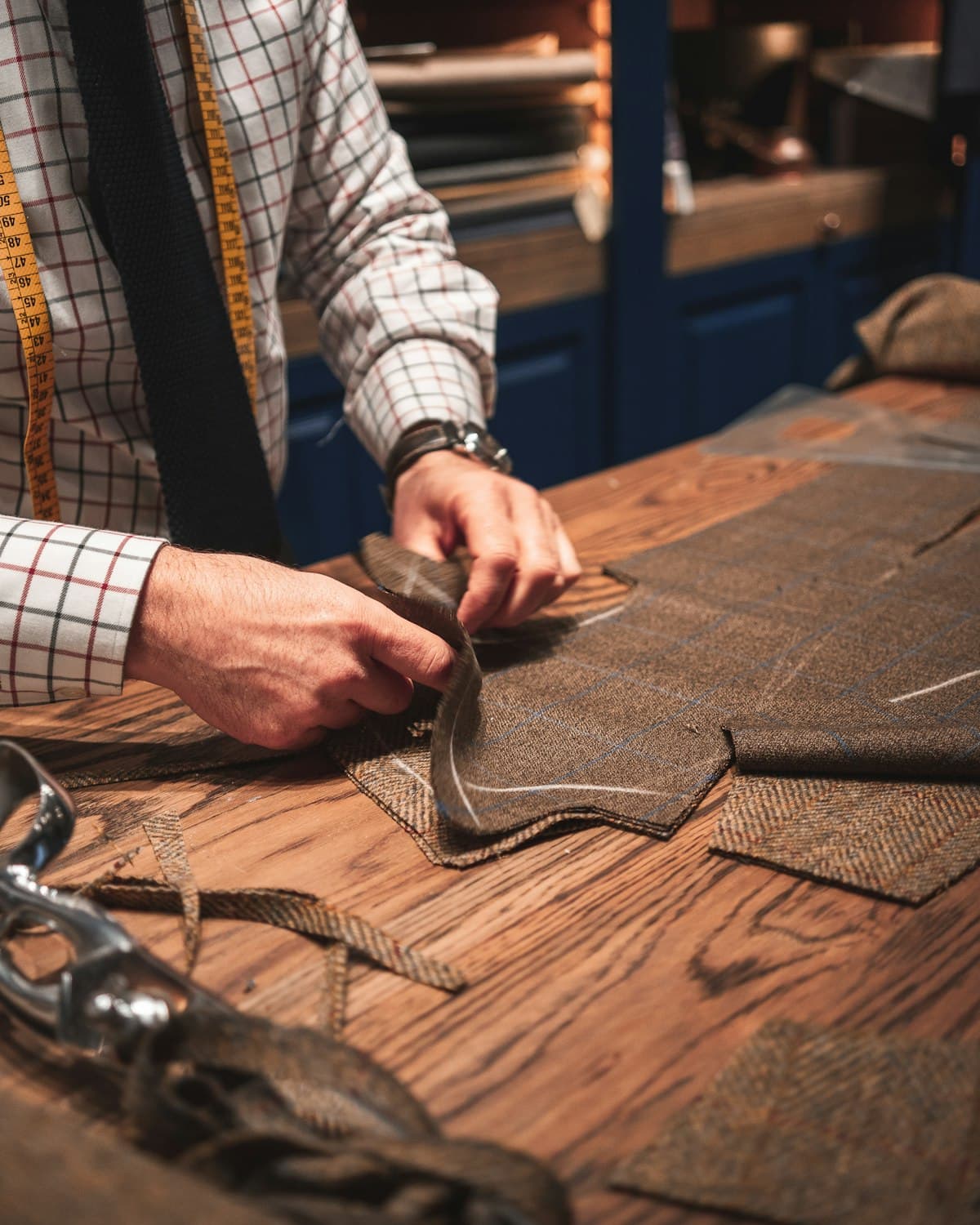 A tailor working cloth on a wooden cutting table